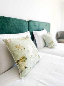 a white bed with a floral pillow on it at Apolo71 Alojamentos in Bragança