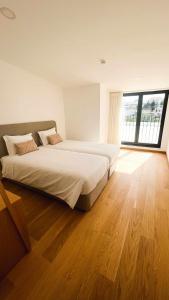 a bedroom with a large bed and a large window at Apolo71 Alojamentos in Bragança