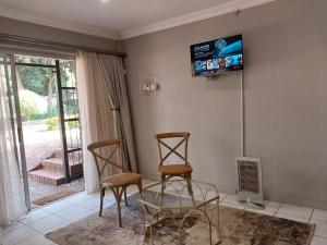 uma sala de estar com duas cadeiras e uma televisão na parede em Lydiana Guesthouse em Pretoria
