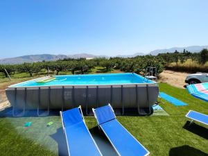 a large swimming pool in a yard with blue chairs at Lovely Country House in Trappeto