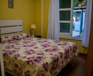 a bedroom with a bed with a floral bedspread and a window at Casa com lareira e lazer, em Campos do Jordao SP in Campos do Jordão +37 photos