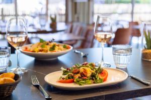 une table avec une assiette de nourriture et des verres de vin dans l'établissement Dormio Resort Berck-sur-Mer, à Berck-sur-Mer