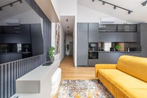 a living room with a yellow couch and a kitchen at Luxurious penthouse with parking in Rīga