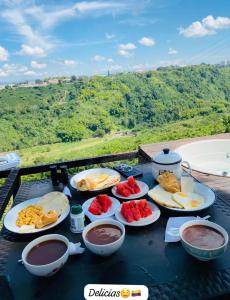 un tavolo con piatti di cibo su un tavolo con vista di Happy Glamping Quindio - Tipo Domo Traslúcido a Calarcá