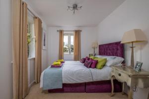 sypialnia z łóżkiem z fioletowymi i zielonymi poduszkami w obiekcie Alice Cottage w mieście Camber