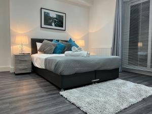 a bedroom with a bed with blue pillows and a rug at Watford Central Apartments - Modern, spacious and bright 1 bed apartments in Watford