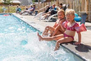 貝爾克濱海的住宿－貝爾克梅爾多米奧度假酒店，两个小女孩坐在游泳池边