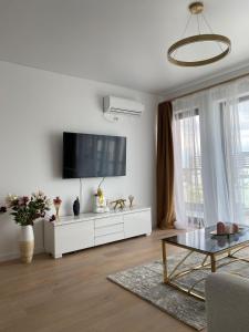 a white living room with a tv on the wall at Queen's Studio Deluxe Mamaia Nord in Mamaia Nord