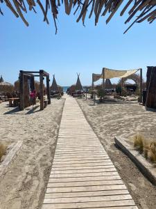 a wooden path on the beach with umbrellas at Queen's Studio Deluxe Mamaia Nord in Mamaia Nord