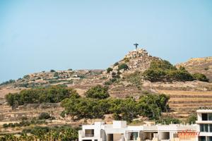 una croce sulla cima di una collina con case di Country views by the sea. Holiday time in Gozo. a Żebbuġ