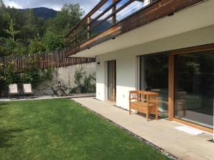 a house with a patio with a grass yard at Chalet n. 5 in Carano