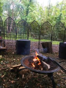 eine Feuerstelle in einem Garten mit einem Zaun in der Unterkunft little vintage caravan with cosy log burner in Canterbury
