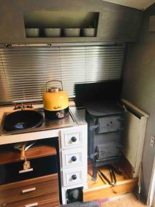 a kitchen with a stove with a pot on it at little vintage caravan with cosy log burner in Canterbury