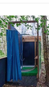 a shed with a hammock in front of a tree at little vintage caravan with cosy log burner in Canterbury