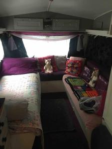 a small room with two beds in the back of a van at little vintage caravan with cosy log burner in Canterbury
