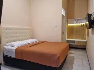 ein Schlafzimmer mit einem Bett und einem TV in der Unterkunft Banana Homestay Prawirodirjan in Yogyakarta