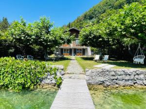 une maison avec un pont sur une étendue d'eau dans l'établissement Les Clapotis chambres pieds dans l eau lac d Annecy, à Angon