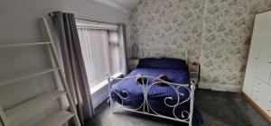 Un dormitorio con una cama azul y una ventana en Cosy, spacious and comfortable family home., en Kirkburton