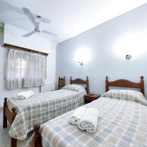 um quarto com 2 camas e uma ventoinha de tecto em Posada del Angel em Neuquén
