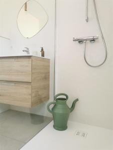 a bathroom with a green vase on the floor at Au Jardin des Deux Roches in Prissé