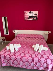 a pink bedroom with a purple bed with white pillows at Appartamento Orchidea in Parghelia