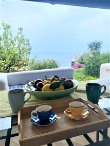 una mesa con dos tazas y un bol de fruta en Casa Surya - Sea view terrace, Isola Salina, en Malfa
