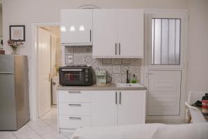 a kitchen with white cabinets and a microwave at Just A Stay apartement in Chios