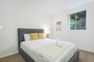 een witte slaapkamer met een groot bed met gele kussens bij Castle HIll Sweet Modern 3BR Apt with 2 Parking in Castle Hill