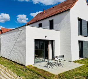 a white building with two chairs and a table at Domaine des diamants blancs de Bondues in Bondues