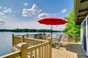 a deck with chairs and a red umbrella at Cozy Cohocton Cottage with Private Beach and Deck! in Cohocton