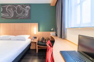 ibis De Panne في دي بان: غرفة في الفندق مع سرير وجهاز كمبيوتر محمول على مكتب