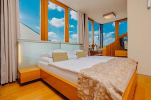 sypialnia z łóżkiem i dużymi oknami w obiekcie Wenceslas Square Hotel - Czech Leading Hotels w Pradze