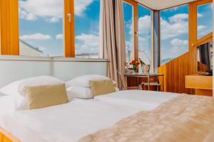 a bedroom with a white bed and large windows at Wenceslas Square Hotel - Czech Leading Hotels in Prague