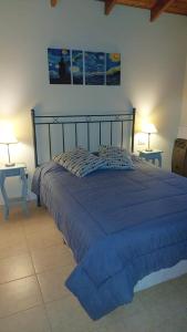 1 dormitorio con 1 cama azul y 2 mesas en Cabañas Lemunko en Sierra de la Ventana