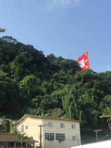 uma bandeira que sobrevoa um edifício em frente a uma montanha em Casa gigante com vista para o mar e piscina em São Vicente