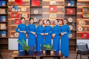a group of women in blue uniforms standing in front of a shelf at Khách sạn Lavie Hotel Quảng Ngãi in Quang Ngai