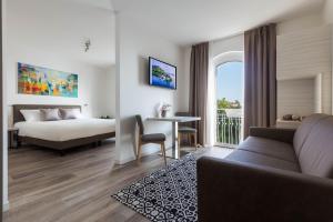 a living room with a couch and a bed and a window at Hotel Giardinetto in Garda