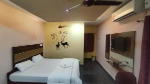 sypialnia z łóżkiem i telewizorem w obiekcie sri Murugan beach paradise hotel w mieście Mahabalipuram
