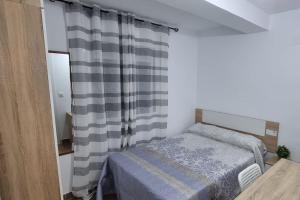 a small bedroom with a bed and a curtain at Piso amplio completo en Almería para 9 personas in Almería
