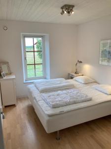 een witte slaapkamer met 2 bedden en een raam bij Fogelbergs EsE in Tofta