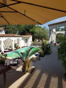 een patio met een parasol en een zwembad bij Appartement dans maison en RDC in Nègrepelisse