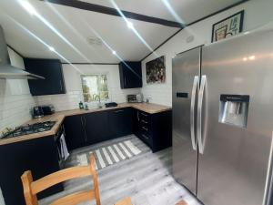 a kitchen with a stainless steel refrigerator and black cabinets at Woodland Hot Tub Retreat in Swarland