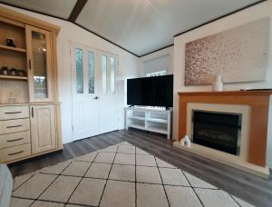 a living room with a fireplace and a flat screen tv at Woodland Hot Tub Retreat in Swarland