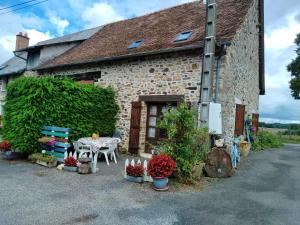 una casa de piedra con una mesa y flores delante de ella en La petite ferme de Lucie et Andréa, en Saint-Vitte-sur-Briance