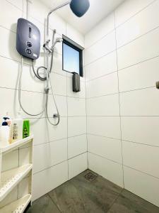 a shower in a white tiled bathroom with a window at Traders garden c180 in Cheras