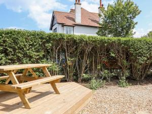 a wooden picnic table in front of a hedge at The Garden House in Whitstable