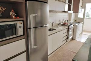 uma cozinha com um frigorífico de aço inoxidável e um micro-ondas em Apto Centro de Criciúma em Criciúma