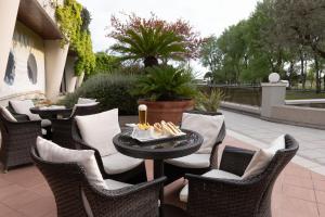 a patio with wicker chairs and a table with candles at Savoy Beach Hotel & Thermal Spa in Bibione