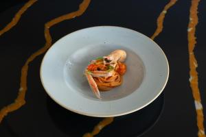 a white plate with pasta and shrimp on a table at Savoy Beach Hotel & Thermal Spa in Bibione