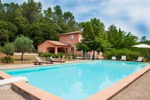 a large swimming pool with a house in the background at Le mas dans les Oliviers in Flassans-sur-Issole